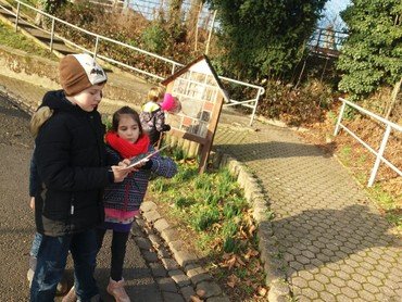 Zwei Kinder vor einem Insektenhotel; sie lesen etwas